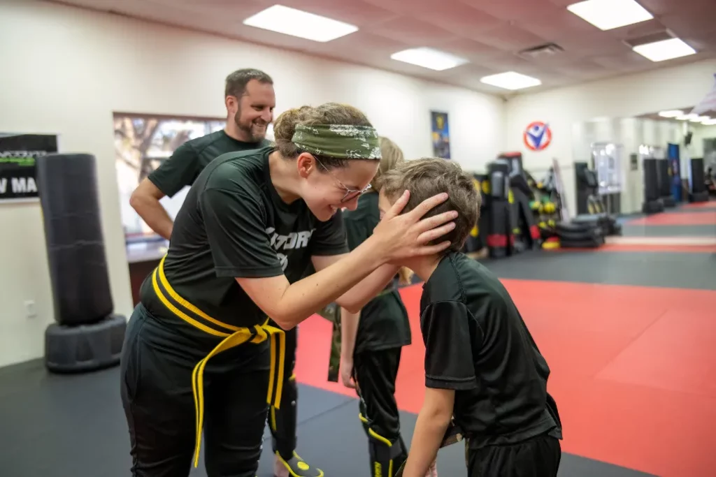Female Instructor Smiling and Holding Head of a Boy During the Karate Basics for Kids in Longwood, Florida